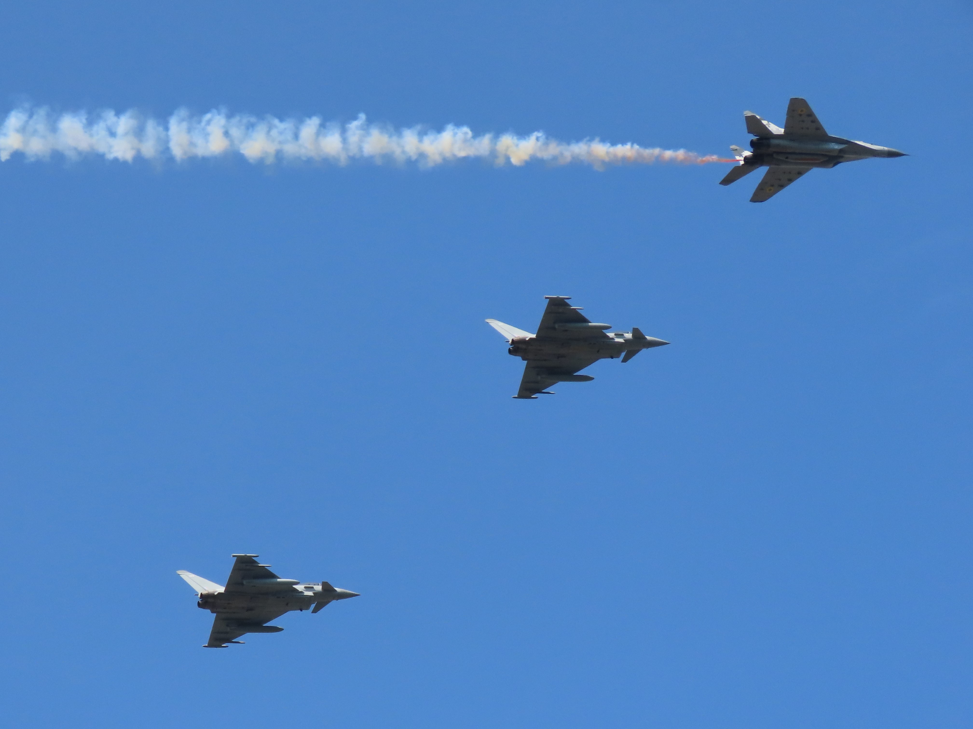 Typhoons fly in formation trailing yellow and blue smoke.